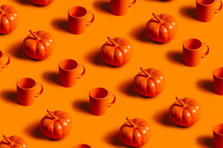 Fall season pattern of orange cups and small orange pumpkins on matching orange background. Creative Halloween or Thanksgiving concept. Autumn breakfast idea. Flat lay.の写真素材