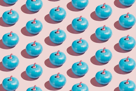 Fall pattern of blue painted pumpkins with pink petioles isolated on a pastel pink background. Creative Halloween or Thanksgiving concept. Autumn food texture. Flat lay.の写真素材
