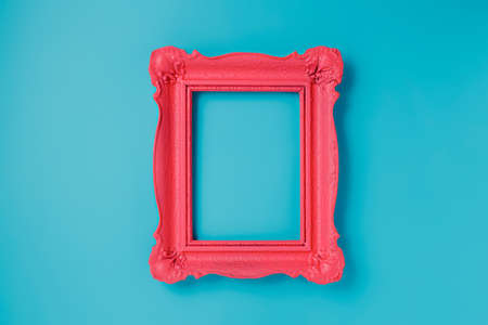 A pink empty frame isolated on the vibrant blue background. Decorative detail, retro inspired backdrop. Creative pop art antique frame concept. Juxtapose of and vintage and contemporary style.の写真素材