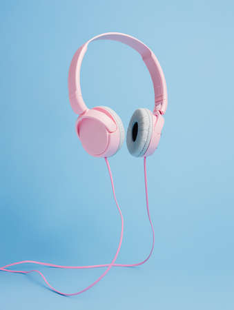 Pink girly headphones flying against bright blue background. Sound and music on. Enjoying loud melody. Creative DJ or party concept. Minimal nightclub visual trend.の写真素材