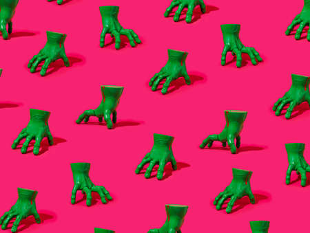 Creative pattern made of green plastic zombie hands on a pink background. Halloween concept.の写真素材