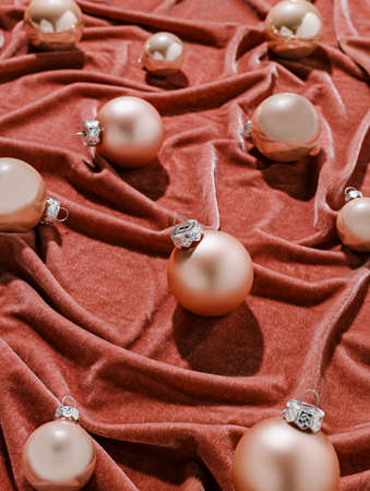 Rose gold Christmas tree balls on a terracotta luxurious soft velvet background. Elegant decorative details and ornaments. Creative Xmas or New year festive holiday concept.の写真素材