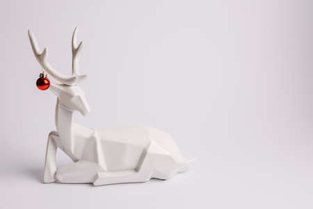 White reindeer with contrast red bauble ornament on its horns isolated on bright white background. Creative Christmas and New Year celebration concept. Minimal festive banner with copy space.の写真素材