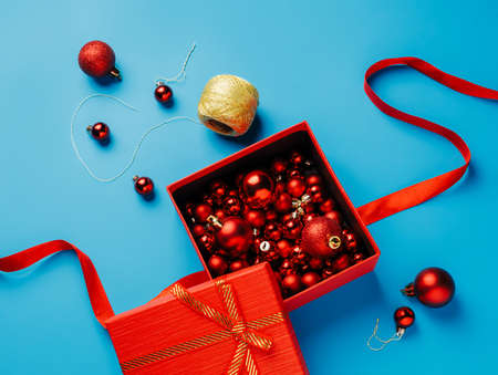 Unboxing Christmas tree baubles and attaching them to golden crochet thread isolated on vivid blue background. New Year and Merry Christmas gifting creative concept. Flat lay.の写真素材