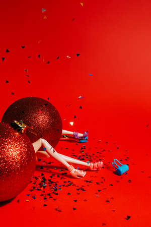 Big red Christmas tree ornament balls with doll legs popping out from the middle on red background....