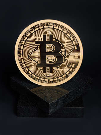 Golden bitcoin on the marble stone podium against black background. Creative cryptocurrency or...