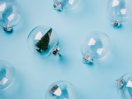 Christmas layout with transparent ball ornament with evergreen fir tree on pastel blue background. Minimal glamour Xmas or New Year celebration concept. Elegant winter holidays texture. Flat lay.の写真素材