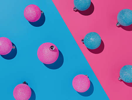 Creative layout made of Christmas baubles on pink and blue background. Minimal New Year concept.の写真素材