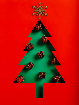 Christmas tree shape made with red gift boxes on vibrant red and green background. Minimal Xmas eve or Happy New Year celebration concept. Elegant winter holidays greeting card. Flat lay.の写真素材