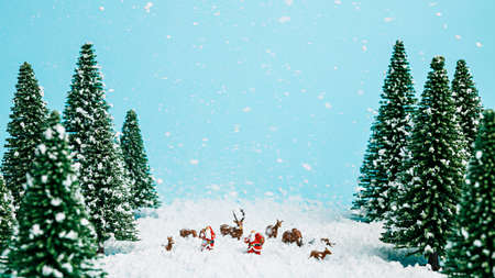 Christmas scene with Santa Claus, pine tree forest, snow and small deer on pastel blue snowy background. Creative Xmas or New Year festive concept. Winter holiday idyllic landscape greeting card.の写真素材