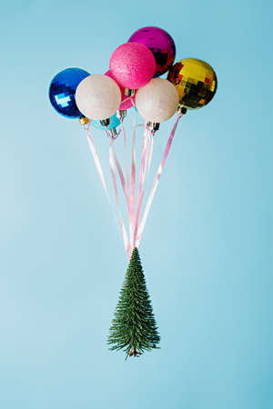 Christmas tree with colorful balloons and ribbons on a blue background.の写真素材