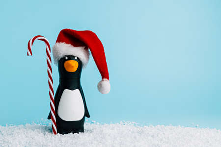 Cute penguin in Santa Claus hat with candy cane on blue backgroundの写真素材