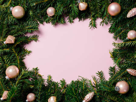 Christmas wreath with fir branches on pink background. Flat lay, top view.