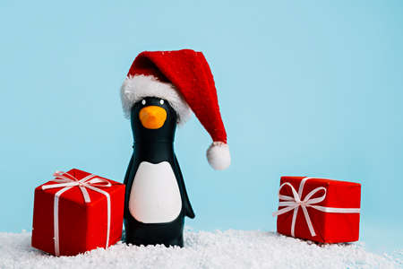 Penguin with Santa Claus hat and gift boxes on blue backgroundの写真素材