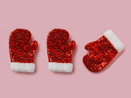 Red glittery christmas mittens with heart on pink background.