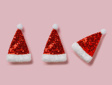 Red Santa Claus hats on pink background. Minimal Christmas concept.