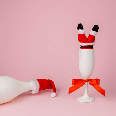 Champagne bottle with Santa's hat on pink background. Minimal Christmas concept.の写真素材