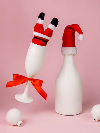 Christmas and New Year composition. Champagne bottle with Santa Claus hat on pink background.の写真素材