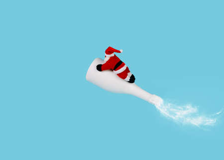Christmas scene with Santa Claus flying on champagne bottle rocket on blue sky background. Creative Xmas or New Year festive concept. Winter holiday funny idea. December celebration banner.の写真素材