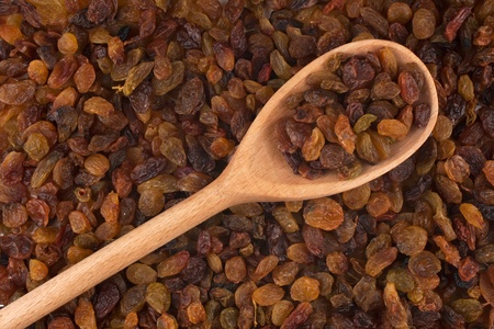 Wooden spoon with raisins is on raisinsの写真素材