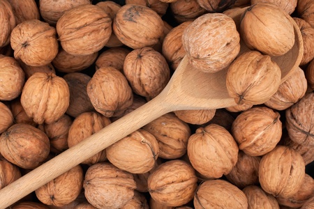 Wooden spoon with three walnuts on a background of a walnut 