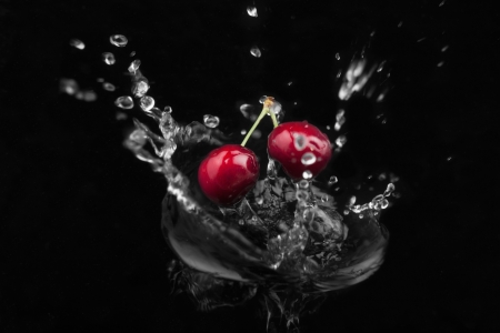 Cherry falling into the water on a black backgroundの写真素材