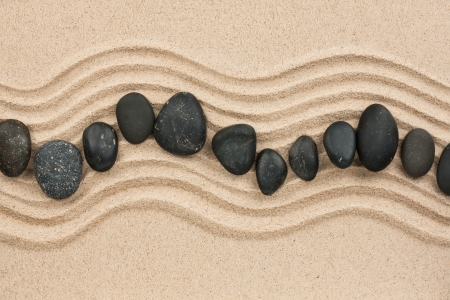 Black stones on the sand, can be used as backgroundの写真素材
