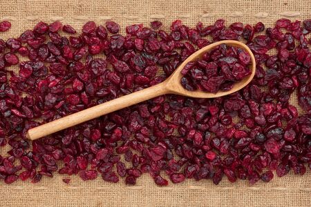 Wooden spoon with  cranberries, lying on sackclothの写真素材