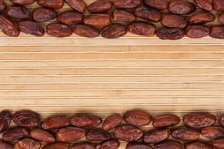 Dried dates lying on a bamboo mat, as backgroundの写真素材