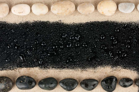 Black and white Zen stones on sand and water drops, with space for textの写真素材