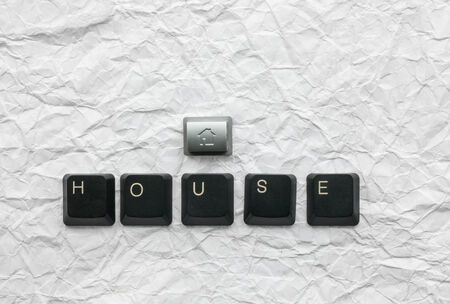 Keyboard keys laid out the word house on a crumpled paperの写真素材