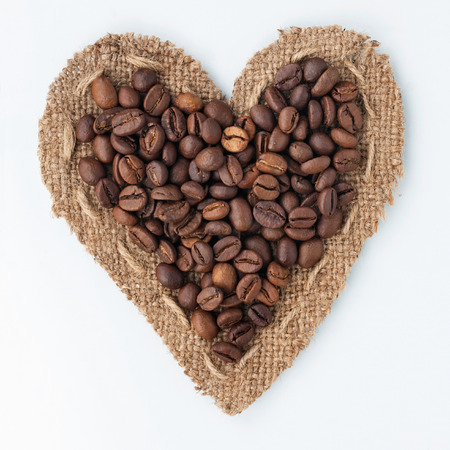 Heart of burlap and coffee beans lying on a white background,can be used as textureの写真素材