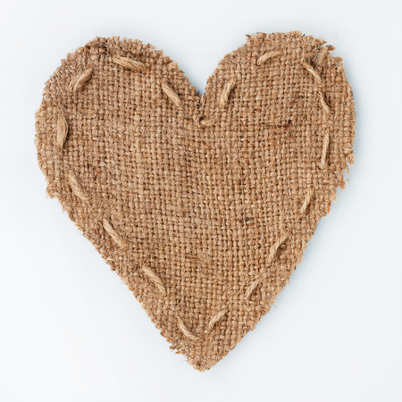 Symbolic heart of burlap lies on a white background, with place for your textの写真素材