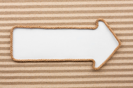 Pointer made of rope with a white background on the sand, with place for your textの写真素材