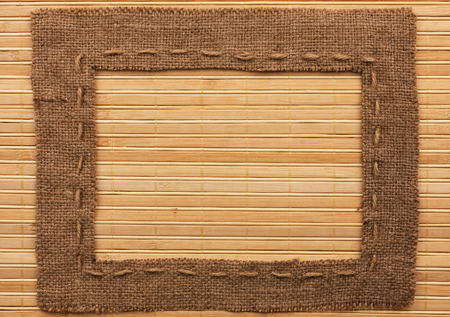 Frame of burlap, lies on a bamboo mat, with place for your textの写真素材