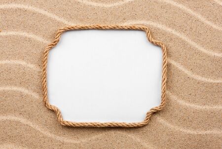 Frame made of rope with a white background on the sand, with place for your textの写真素材