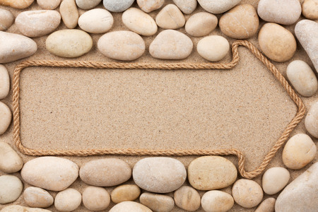 Pointer made of rope with white stones, lying on the sandの写真素材