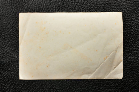 Old crumpled paper lying on black leather, as a frame, textureの写真素材