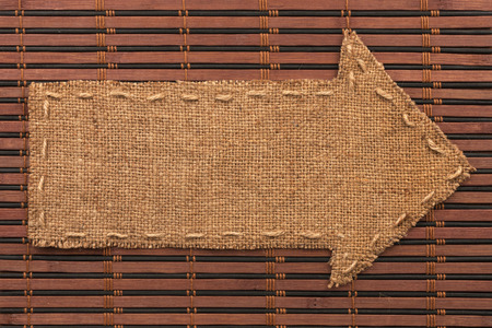 Arrow made of burlap lies on a bamboo matの写真素材