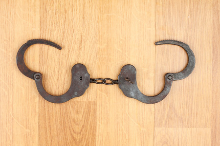 Opened  handcuffs lying on the wooden floor, as a background