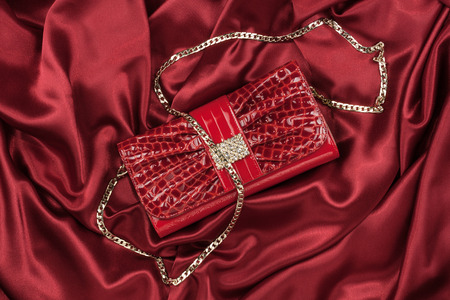 Red lacquer bag lying on a red silk, as backgroundの写真素材