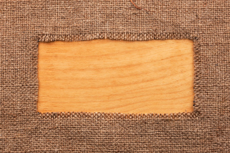 Frame made of burlap  lying on a wooden surface, with space for your textの写真素材