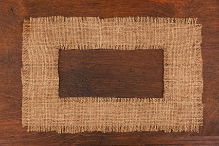 Frame made of burlap  lying on a wooden surface, with space for your textの写真素材