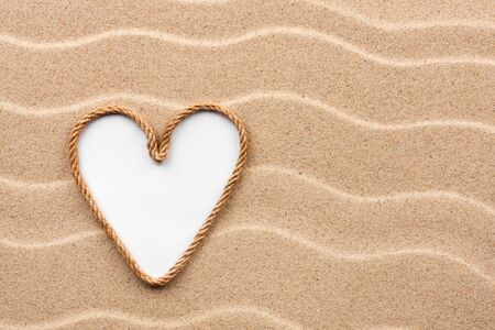 Heart made of rope with a white background on the sand, with place for your textの写真素材
