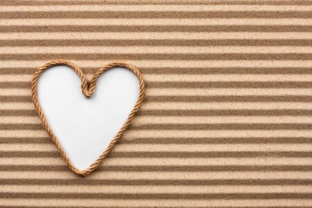 Heart made of rope with a white background on the sand, with place for your textの写真素材