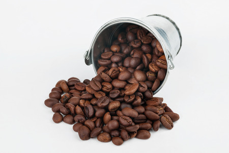 Coffee beans spilling out of bucket, on a white backgroundの写真素材