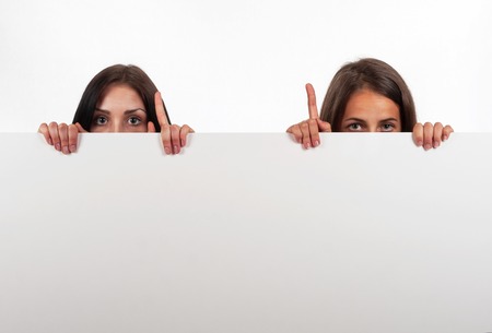 Beautiful brunette and blonde looking  and indicate, on white backgroundの写真素材