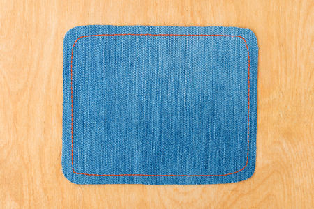 Light frame made of denim is lying on a light wood surface