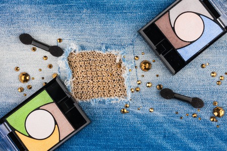 Women's cosmetics lying on torn jeans, with space for your textの写真素材