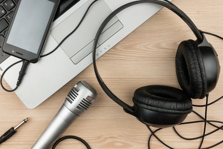 Laptop, microphone, headsets lies on a wooden table, background, top viewの写真素材